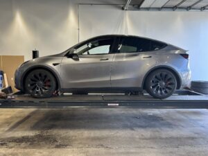 Grå bil på værkstedslift i garage