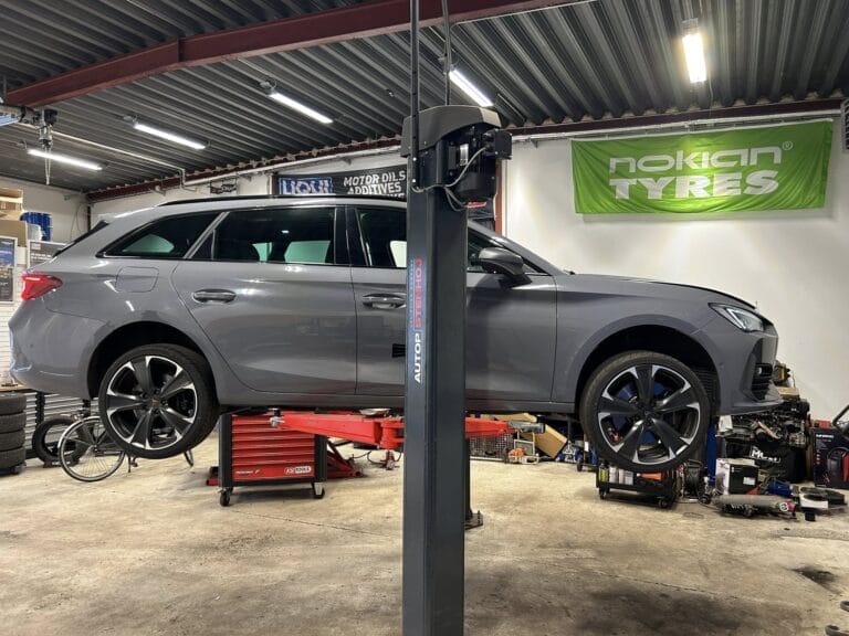 Grå bil på liften i autoværksted