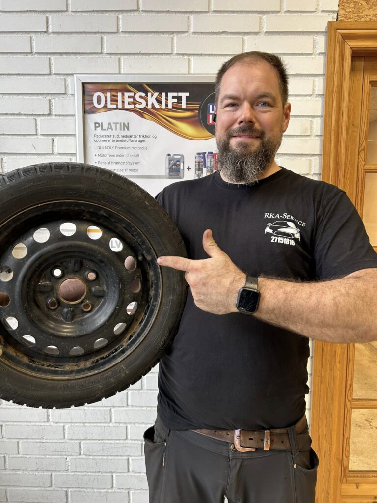 Mand viser bildæk i værkstedet